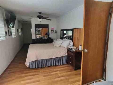 Dormitorio principal amplio con piso de madera y abanico de techo