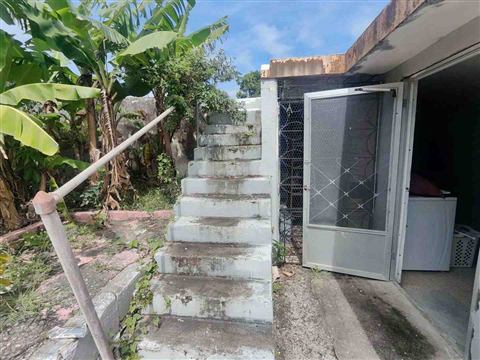 Escalera exterior de hormigón que sube al segundo nivel, junto al área de lavandería